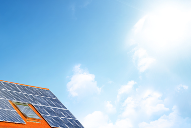 Dach mit Photovoltaikanlagen unter blauem Himmel und strahlender Sonne.