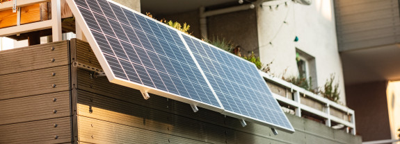 Solarmodule auf dem Balkon eines Gebäudes, montiert an einer Holzverkleidung.