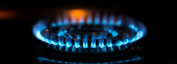 Blaue Flamme auf einem Gasherd mit dunklem Hintergrund.
