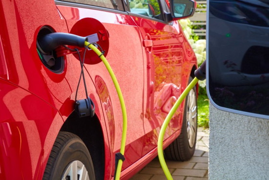 Rotes Elektroauto wird an Ladestation aufgeladen