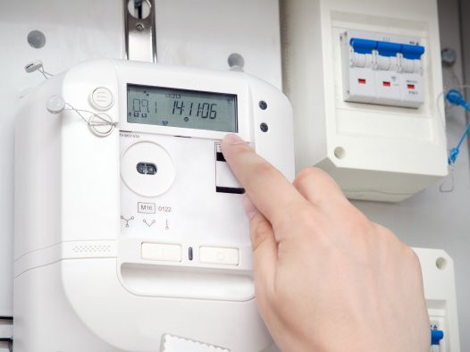 Hand drückt auf digitalen Energiezähler mit Anzeige