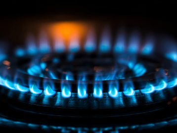 Blaue Flamme auf einem Gasherd mit dunklem Hintergrund.