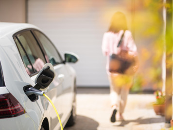 Elektroauto wird geladen, Person geht im Hintergrund weg